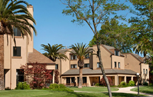 A tan building with palm trees in front of it.